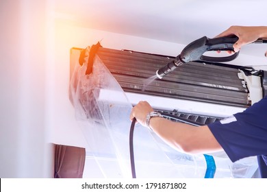 The Technicians Are Cleaning The Air Conditioner By Spraying Water. Hand And Water Spray Are Cleaning The Air Conditioner. 