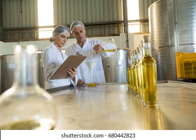 Technicians examining olive oil in factory - Powered by Shutterstock