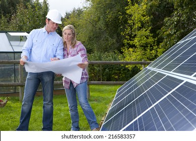 Techniker, die Blaupausen halten, die in der Nähe großer Solarpaneele sprechen