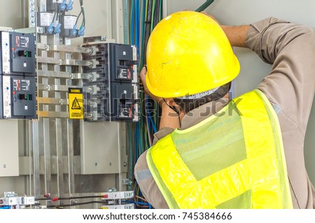 Technicians are installing a power supply at the control cabinet.