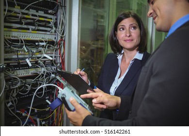 Technicians interacting with each other while analyzing server in server room - Powered by Shutterstock