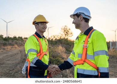 Technicians man making handshake while work in the wind turbines field. Innovation engineer men wearing safety gear, develop environmental renewable clean energy outdoors at windmill power farm. - Powered by Shutterstock