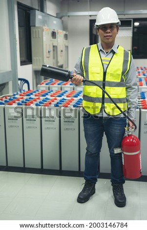 Technicians prepare fire extinguishers for safety in the electrical room.