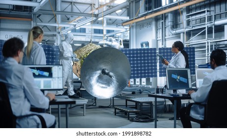 Technicians In Protective Suits Working On Satellite Construction, Under Chief Engineer Control. Aerospace Agency Manufacturing Facility: Scientists Assembling Spacecraft. Space Exploration Mission