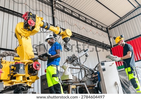 Technicians test and troubleshoot a robotic arm in an industrial workshop, using a laptop and hands-on inspection to support maintenance, upgrade and automation performance.