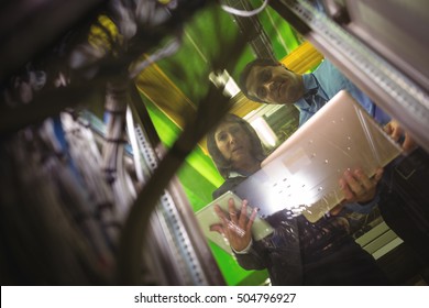 Technicians using digital tablet and laptop while analyzing server