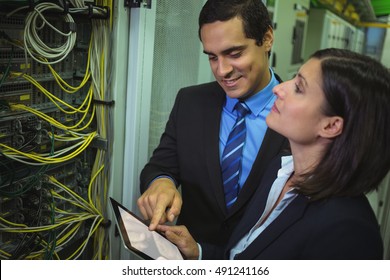 Technicians using digital tablet while analyzing server in server room - Powered by Shutterstock