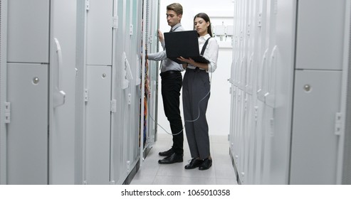 Technicians using laptop while analyzing server in server room