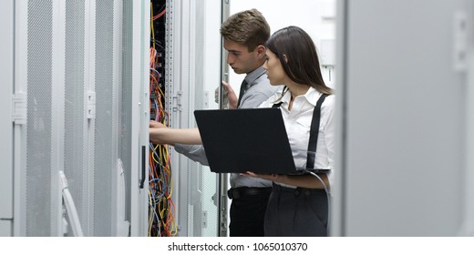 Technicians using laptop while analyzing server in server room