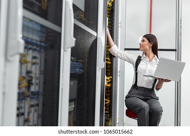 Technicians using laptop while analyzing server in server room