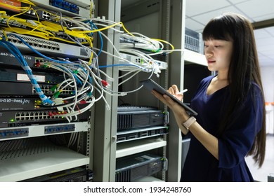 Technicians using laptop while analyzing server in server room.