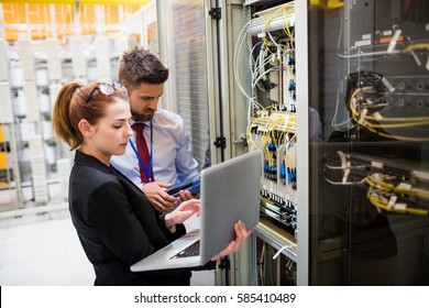 Technicians using laptop while analyzing server in server room - Powered by Shutterstock