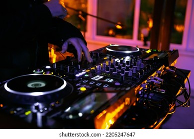 Techno dj playing music set on party. Disc jockey plays tracks on concert stage in night club. Disk jokey midi controller with turntables and sound mixer