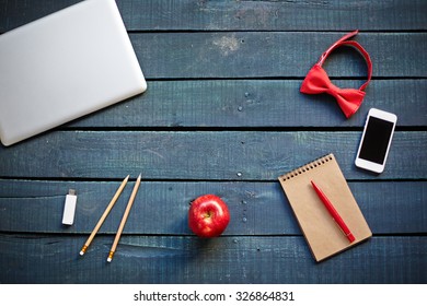 Technological devices, bowtie, red apple, pencils and notebook with pen on workplace - Powered by Shutterstock