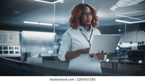 Technological Software Engineering Department Manager Standing and Using a Laptop Computer. Black Female Looking in the Distance and Thinking while Working in the Office