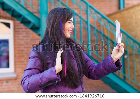 Technologies, urban and people concept - Pretty girl with long coloured hair takes a selfie on the rooftop