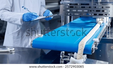 Technologist in blue gloves checking puff pastry production line machinery.