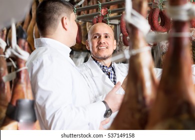 Technologist with butcher checking drying wurst at factory - Powered by Shutterstock