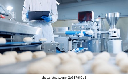 Technologist checking dough quality on confectionery production line in pastry factory.