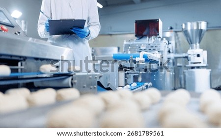 Technologist checking dough quality on confectionery production line in pastry factory.