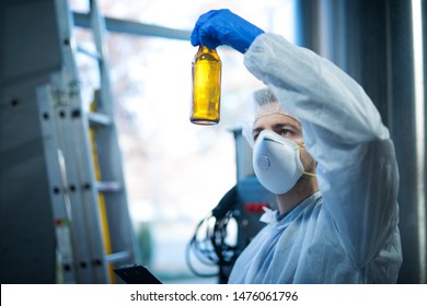 Technologist Expert In Beer Production Factory Holding Glass Bottle And Checking Quality. Food And Beverage Quality Control.