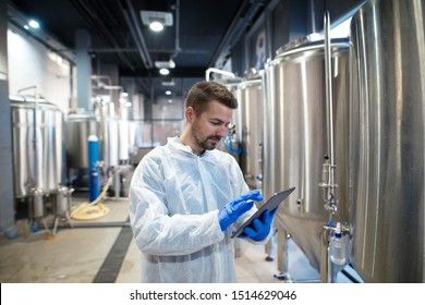 Technologist Expert Using Tablet Computer In Food Factory Production Line. Factory Worker Controlling Production.