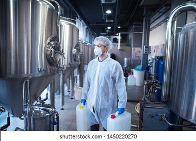 Technologist Industrial Worker Holding Plastic Canisters About To Change Chemicals In The Food Processing Machine. Cleaning In Food Factory.