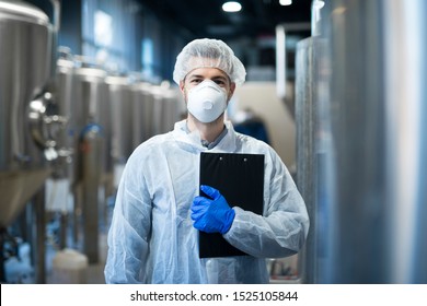 Technologist With Protective Mask And Hairnet Standing At Factory Production Line. Food Or Beverage Processing Factory.