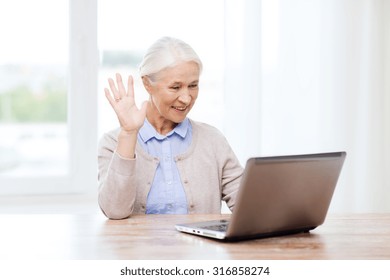 Technology, Age, Gesture, Communication And People Concept - Happy Senior Woman With Laptop Computer Having Video Chat At Home And Waving Hand