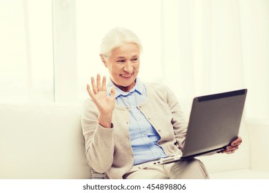 technology, age, gesture, communication and people concept - happy senior woman with laptop computer having video chat at home and waving hand - Shutterstock ID 454898806