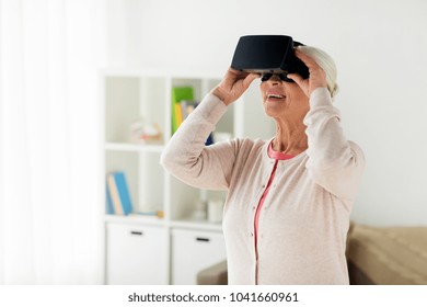 technology, augmented reality, entertainment and people concept - senior woman with virtual headset or 3d glasses playing videogame at home - Powered by Shutterstock