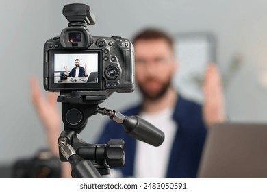 Technology blogger explaining something while recording video at home, focus on camera