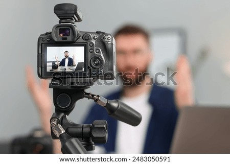 Technology blogger explaining something while recording video at home, focus on camera