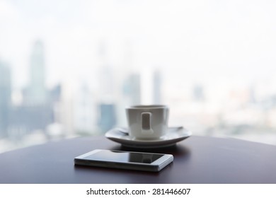 Technology, Business And Modern Life Concept- Close Up Of Smartphone And Coffee Cup On Table At Office Or Hotel Room