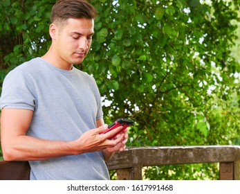 Technology and communication. Handsome man using mobile phone texting on smartphone outdoor in park