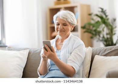 technology, communication and people concept - happy senior woman with smartphone at home
