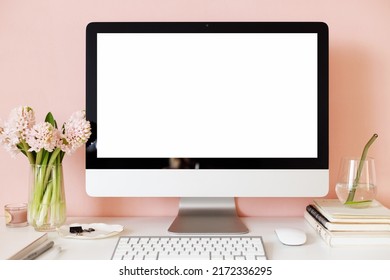 Technology, communication and remote job concept. Nice workplace of female copywriter with fresh flowers, glass of water and generic desktop computer with blank display for your advertising content