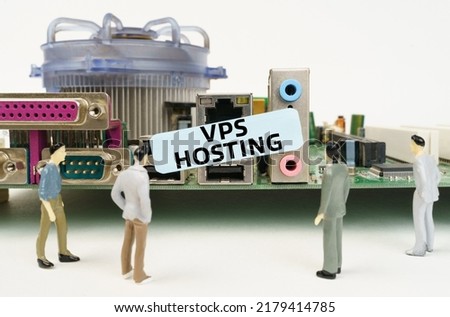Technology and computer concept. Figures of people are standing near the motherboard and looking at the sticker with the inscription - Vps Hosting