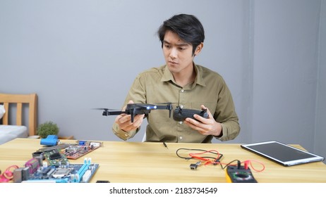 Technology Concept Of 4k Resolution. Asian Man Fixing Drone In Room. Check For Damage.