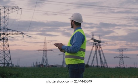 technology concept with high voltage power lines. electrical engineer helmet digital tablet sunset. power engineer power plant high voltage voltage energy. concept electrical engineer working sunset. - Shutterstock ID 2144445849