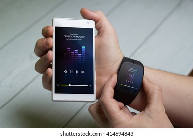 Technology Concept: Man Playing Music On Smart Watch And Phone.  Screen Graphics Are Made Up.