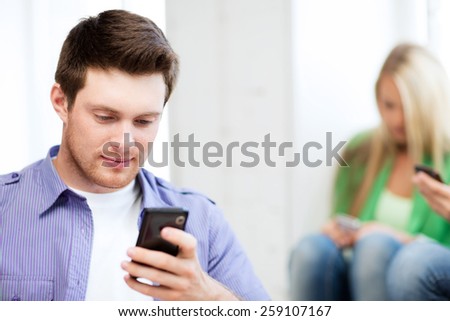 technology concept - student looking at phone and tiping