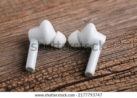 Technology concept : wireless headphone or ear bud on wooden background.