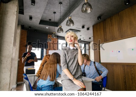 technology consept.fair-haired lady is sitting at the end of the desk with smartphone berore the business meeting