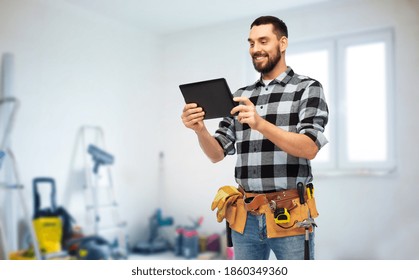 Technology, Construction And Repair Concept - Happy Smiling Worker Or Builder With Tablet Pc Computer And Tools Over Room With Building Equipment Background