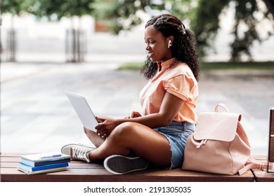 technology, education and people concept - happy smiling african american student girl in earphones with laptop computer and books in city - Powered by Shutterstock