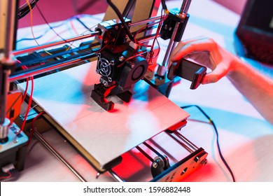 Technology and engineering concept - Male engineer working at night in the lab, he is adjusting a 3D printer components.