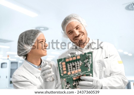 Technology engineers developing new generation microchips and electronic equipment inside factory.