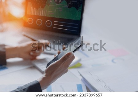 Technology and financial advisory services concert. Businesswoman working on smartphone with laptop computer with advisor showing plan of investment to clients at table office. Digital marketing.