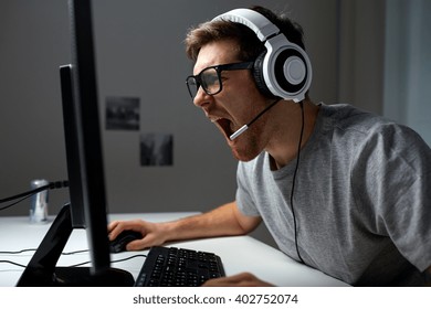 Technology, Gaming, Entertainment, Let's Play And People Concept - Angry Screaming Young Man In Headset With Pc Computer Playing Game At Home And Streaming Playthrough Or Walkthrough Video